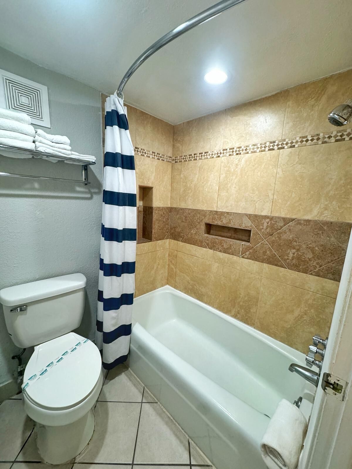 Et badeværelse med toilet, badekar og bruseforhæng.