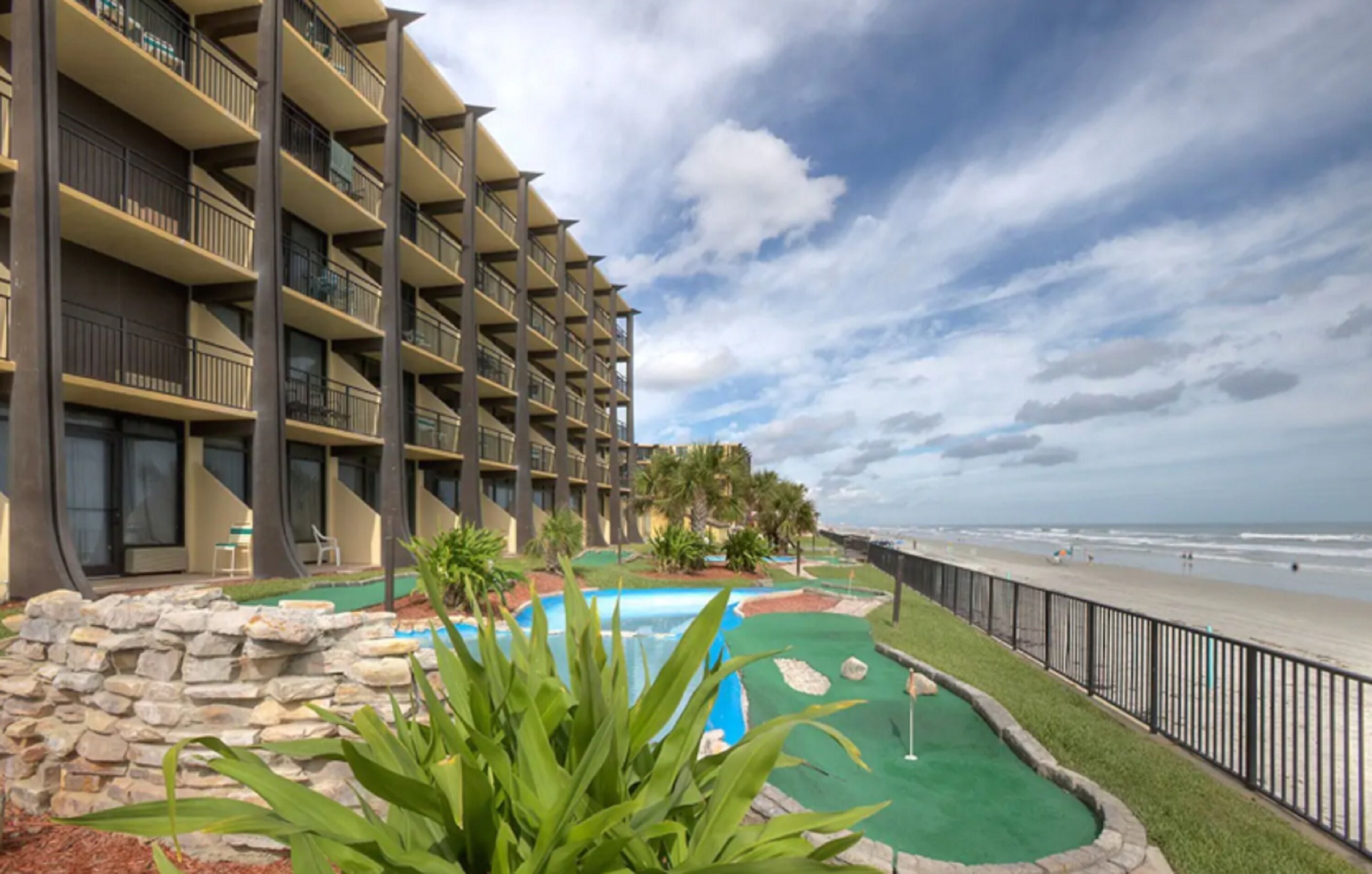 A hotel with multiple balconies, a pool area, and a view of the beach.