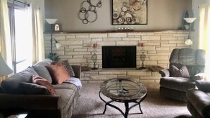 Una sala de estar acogedora con chimenea de piedra, dos sofás, una mesa de centro y decoración mural.