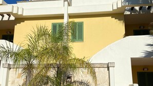 A building with a white facade, green shutters, and a wooden pergola. - Sea Villa (Baia Verde)