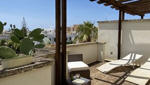 A rooftop terrace with wooden pergola, cushioned seating, and a cactus plant. - Sea Villa (Baia Verde)