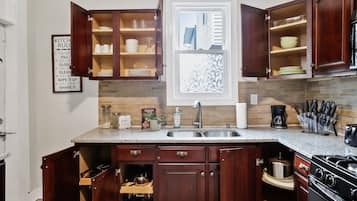 A kitchen with wooden cabinets, a granite countertop, a stainless steel sink, and a stove.