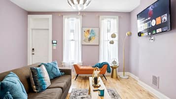 A living room with a brown sofa, orange armchair, and a coffee table with a vase and cup.
