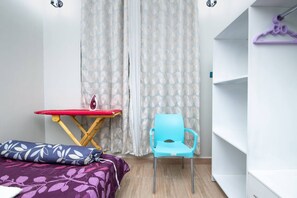 Cozy retreat with a single bed, ironing station, and wardrobe.