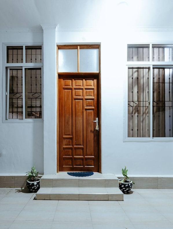 Traditional entrance with a glass panel door, flanked by windows with metal grilles.