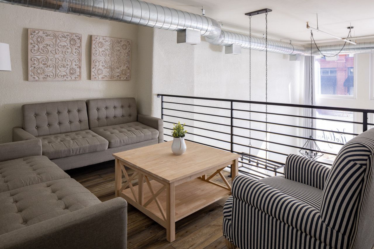 A modern living room with a grey sofa, a striped armchair, and a wooden coffee table.