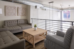 A modern living room with a grey sofa, a striped armchair, and a wooden coffee table.