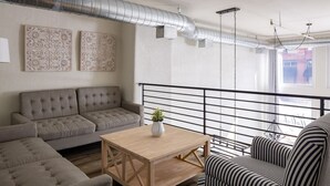 A modern living room with a grey sofa, a striped armchair, and a wooden coffee table. - Main Street Farmhouse. City Retreat by Hollyhock (Louisville)