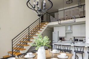 A modern kitchen with white cabinets, a central island, and a dining area with a wooden table and black chairs.