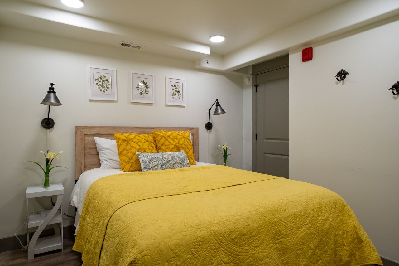 A bedroom with a bed, bedside tables, and wall-mounted lamps.