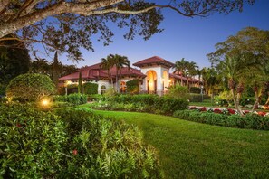 A well-maintained garden with a variety of plants and flowers, a large tree, and a building with a red-tiled roof and arched windows. - Mediterranean Villa in the heart of Naples! Location & Luxury!  (Naples)