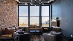 Un salon moderne avec des canapés en cuir, une table basse et une grande fenêtre donnant sur le paysage urbain.