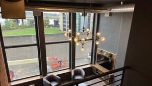 Un intérieur moderne avec une grande fenêtre, un luminaire suspendu et un espace salon.