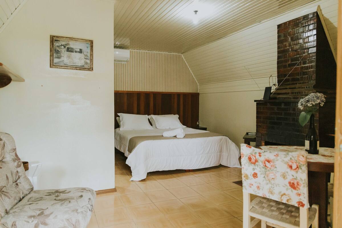 Une chambre à coucher avec un lit, une chaise, une table et une cheminée.