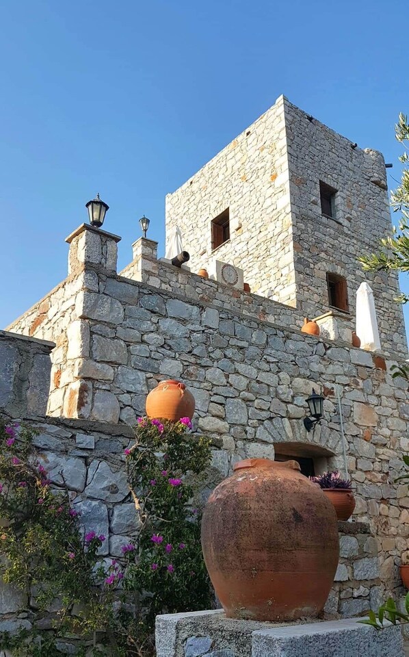A stone building with a tower, terracotta pots, and a lamp post.
