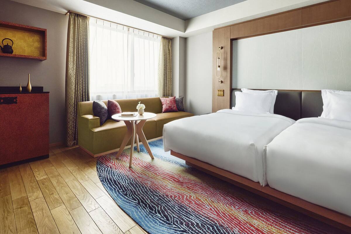 Hotellihuone, jossa on suuri sänky, sohva, pieni pöytä ja työpöytä.