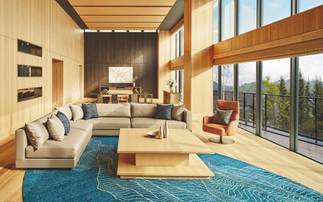 A modern living room with a sectional sofa, a coffee table, and a view of the outdoors through large windows.