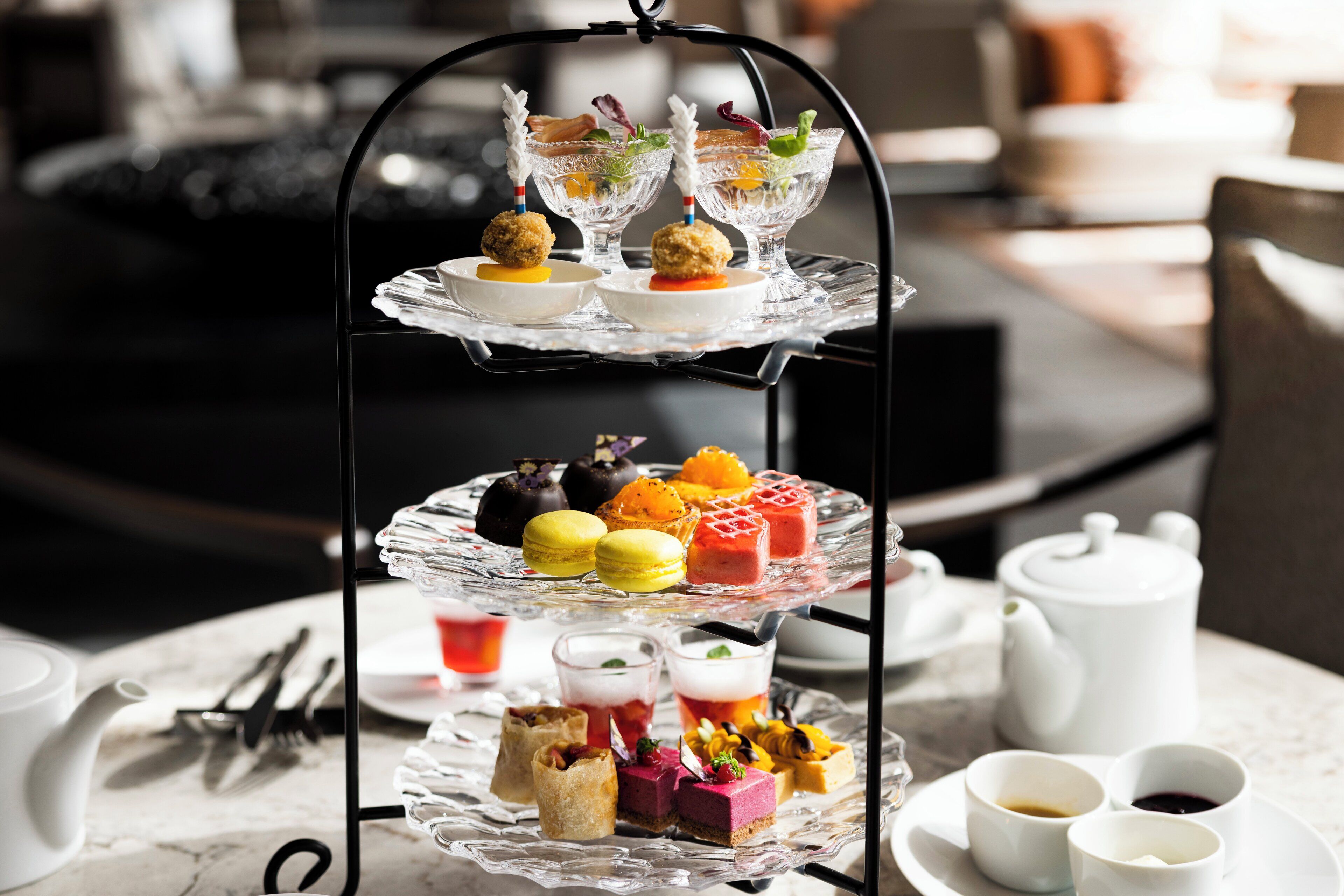 A three-tiered dessert display with various pastries and drinks on a table.