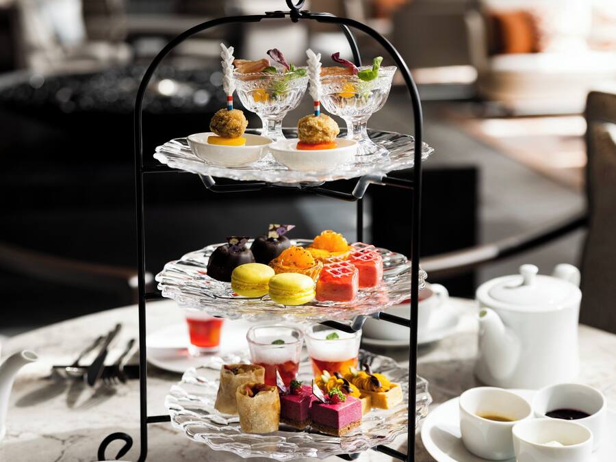A three-tiered dessert display with various pastries and drinks on a table.