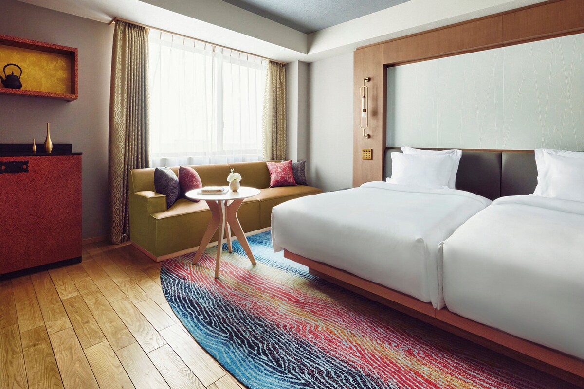 A hotel room with a large bed, a sofa, a small table, and a desk.