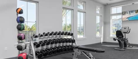 Een sportschool met gewichten, een bank en trainingsapparatuur.