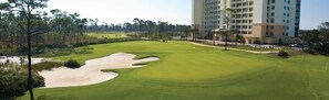 A golf course with bunkers, a water hazard, and a large hotel building in the background. - Paradise Found at Lost Key Resort: Tropical Bliss (Pensacola)