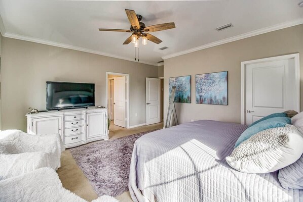 A bedroom with a bed, a ceiling fan, a TV, a dresser, and artwork on the walls. - Paradise Found at Lost Key Resort: Tropical Bliss (Pensacola)