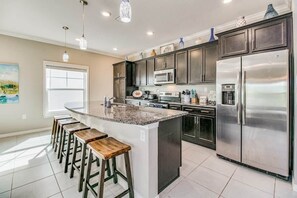 A kitchen with a central island, stainless steel appliances, and bar stools. - Paradise Found at Lost Key Resort: Tropical Bliss (Pensacola)