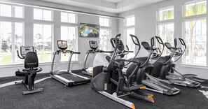 A gym with treadmills, ellipticals, and a stationary bike, large windows, and a painting on the wall. - Paradise Found at Lost Key Resort: Tropical Bliss (Pensacola)