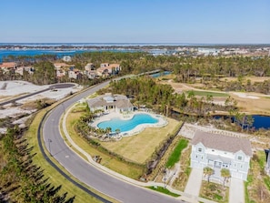 A residential area with a swimming pool, a curved road, and houses.
