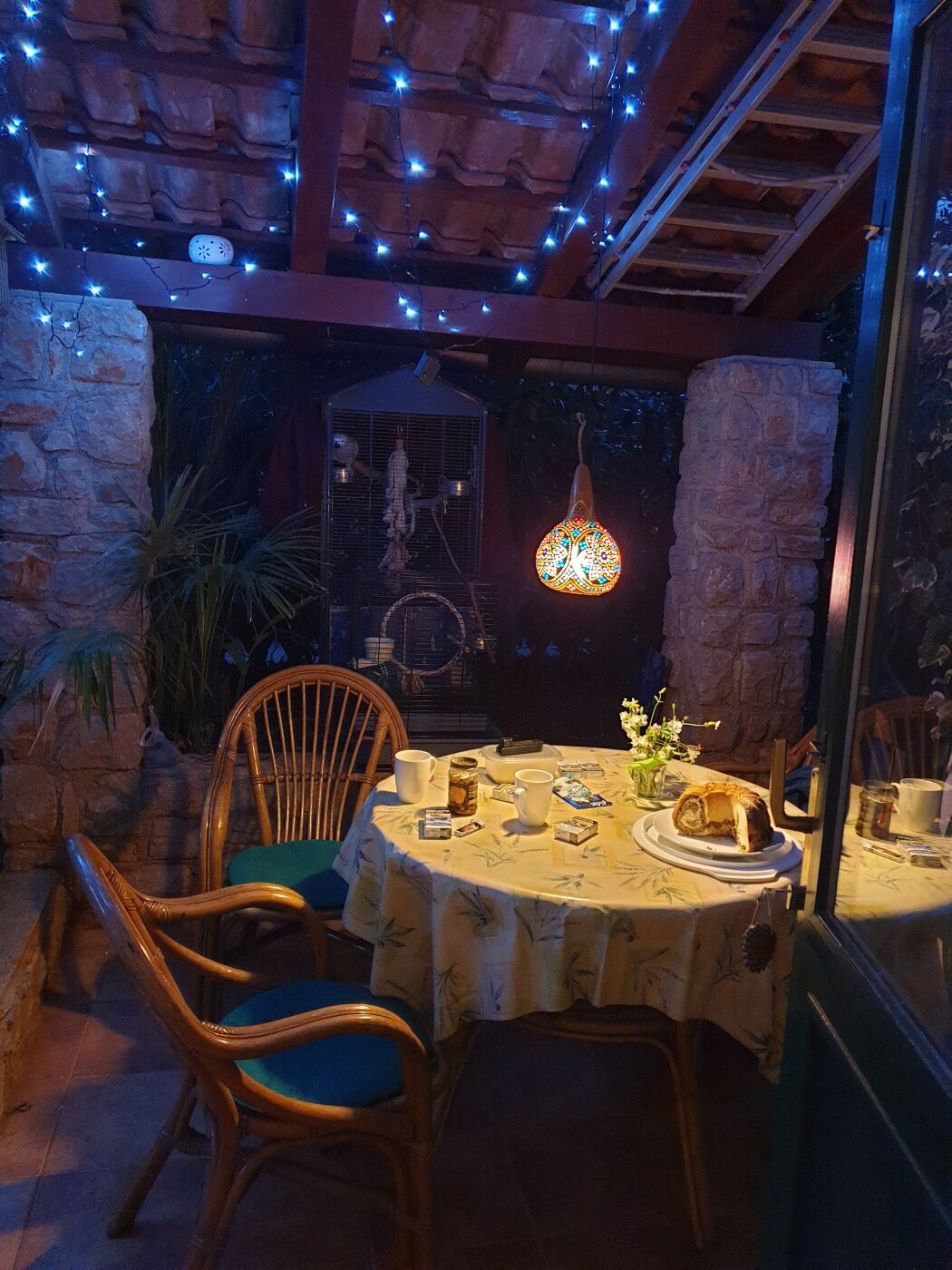 Un espace de restauration en plein air avec une table dressée pour deux personnes, entouré de murs en pierre et de chaises en bois.