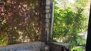 Un espace patio avec une table ronde et une chaise, une horloge décorative en métal et un mur en pierre.