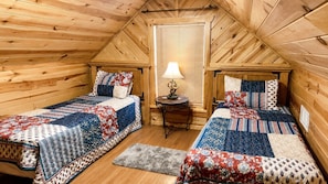Een gezellig slaapkamer op zolder met twee bedden, een tafeltje en een raam met zonwering.