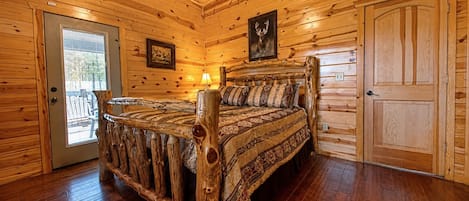 A log cabin bedroom with a wooden bed, a door, and a window.