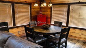 Un intérieur en bois avec une table ronde, quatre chaises, un buffet rouge et un canapé en cuir.