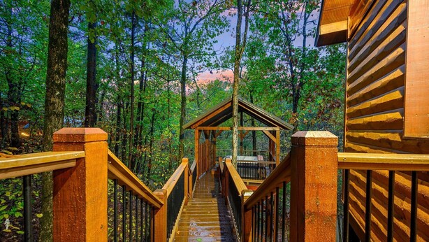 A wooden staircase leading to a covered wooden structure in a forest. - Logan's Bluff Cabin at Hochatown (Broken Bow)
