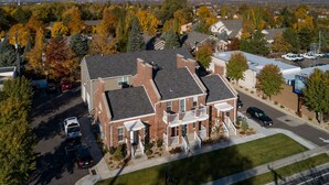 A large brick building with a central entrance and a covered porch, surrounded by trees and a parking lot.