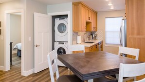 A compact kitchen with a built-in washer and dryer, wooden cabinets, a sink, and a dining table with chairs.