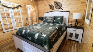 Ein Schlafzimmer einer Holzhütte mit einem Bett, einem Nachttisch und einer Wandlampe.