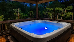 Een hottub op een houten terras, met uitzicht op dennenbomen.