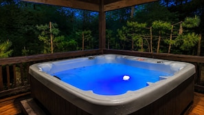 Ein Whirlpool auf einer Holzterrasse mit Blick auf Kiefern.