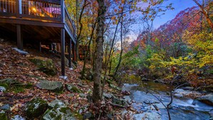 A wooden deck with a view of a forest and a stream.