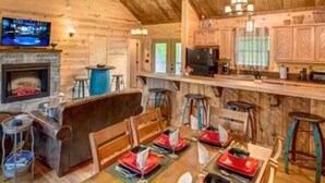 L'interno accogliente di una baita con zona pranzo per quattro persone, cucina con pensili in legno e camino.