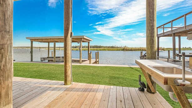 Een houten terras met uitzicht op een meer, een prieel en een steiger.