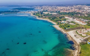Vista aérea de uma cidade costeira com praia, edifícios residenciais e um porto de iates.