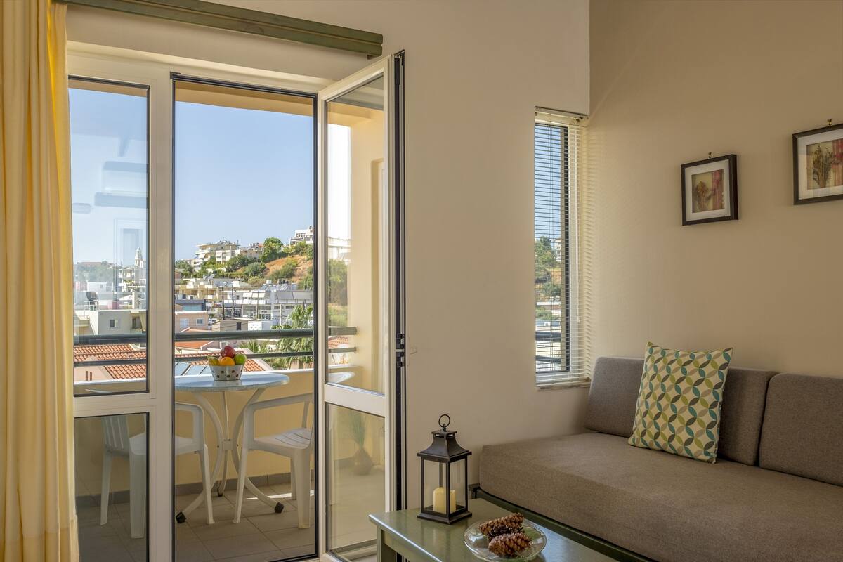 A balcony with a table, chairs, and a bowl of fruit.