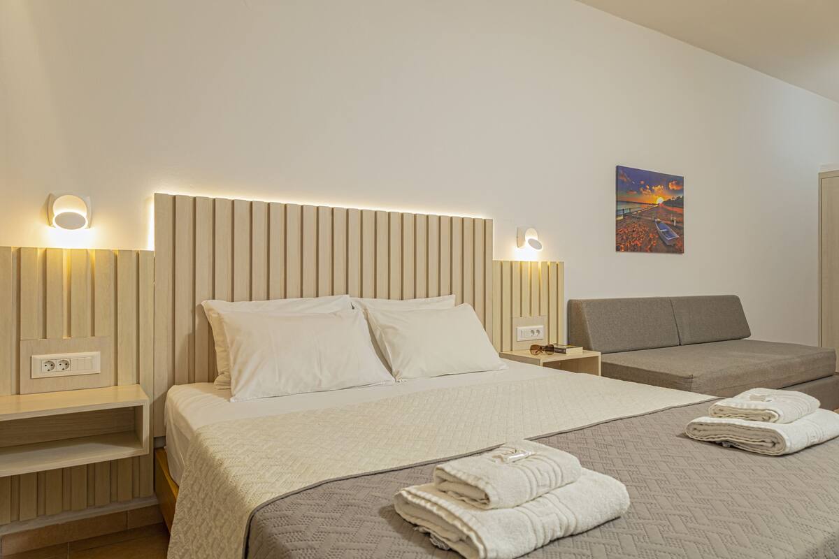 A hotel room with a bed, a sofa, and a painting on the wall.