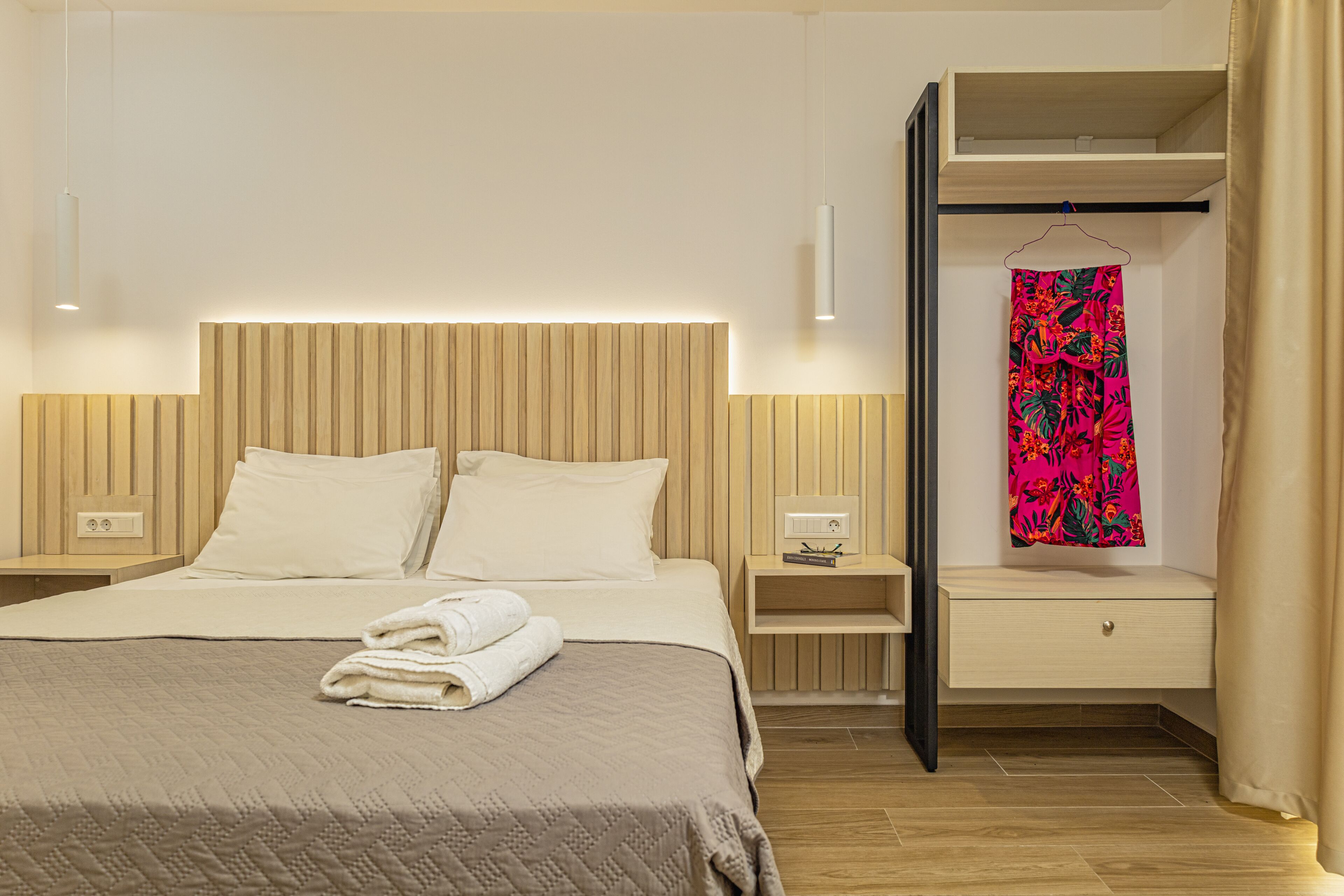 A hotel room with a bed, bedside tables, a wardrobe, and a hanging garment.