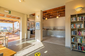 A spacious indoor area with a kitchen, dining area, and bookshelves. - Theos village apartments (Chania)
