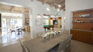 A spacious dining area with a pool table, a kitchen with wooden cabinets, and a dining table set with vases of flowers. - 30 Days+ at a Palm Springs Oasis (Palm Springs)